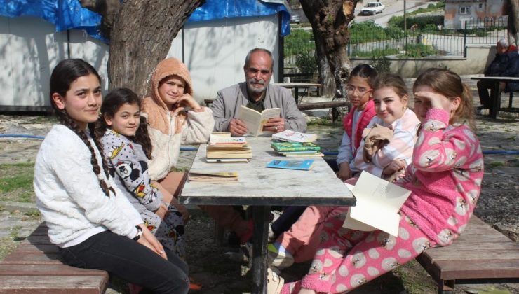 Eline kitabı alan muhtar, çocuklara örnek olmak için birlikte kitap okuyor